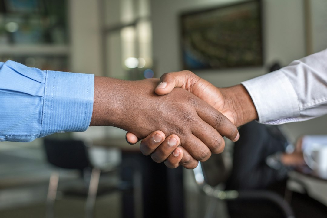 Stretta di mano tra contitolari dopo l'accordo sulla gestione condivisa del marchio